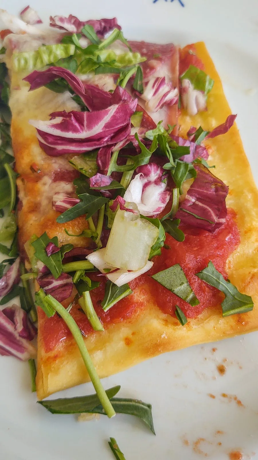 Una teglia di pizza al taglio con rucola e radicchio